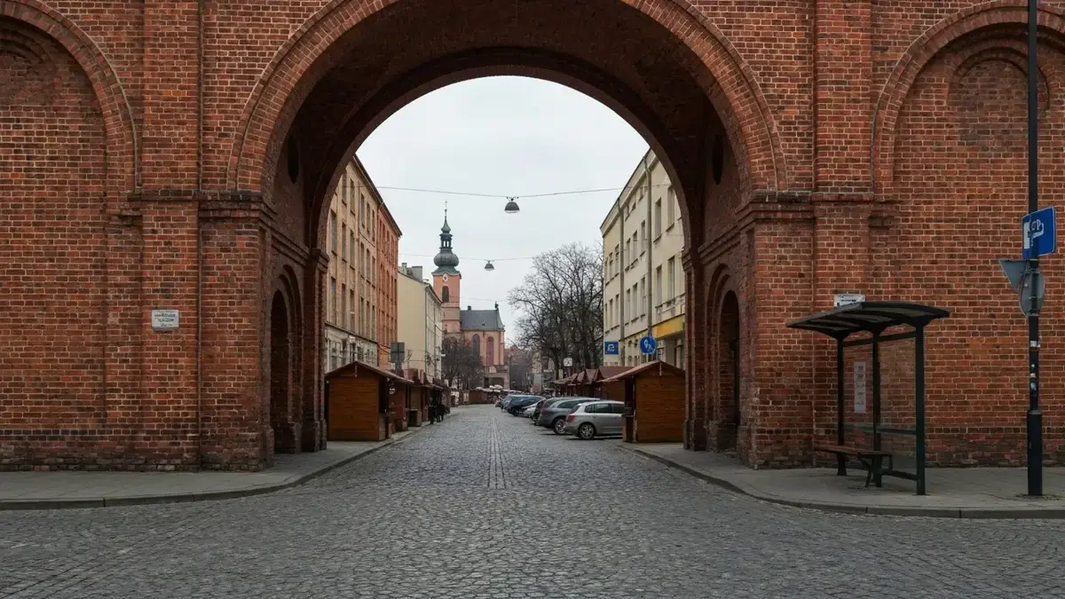 Zimowy jarmark w Nikiszowcu przy ceglanej zabudowie i wąskiej ulicy z zaparkowanymi autami
